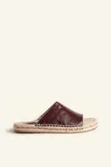 Sandalias tipo alpargata con capellada de cuero charol color bordó y planta tejida en fibra natural de yute. Presentan costuras a mano en color blanco y suela de goma.