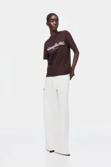 Remera marrón oscuro de algodón con cuello redondo, mangas cortas y estampa frontal en color blanco con las leyendas "Simplicité." y "Douceur de Vivre".
