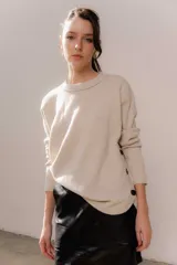 Buzo liviano de cuello redondo, con detalle de aberturas laterales decoradas con botones negros. Presenta un diseño de calce holgado y mangas largas.