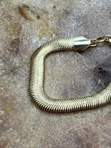 Pulsera dorada con diseño de escamas de serpiente.