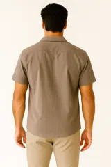 Camisa de lino color verde militar, de corte holgado, con cuello tipo solapa, botones frontales y manga corta.