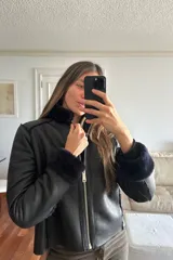Campera reversible de corte recto y largo a la cadera. Un lado presenta un acabado de napa negra, mientras que el otro lado está confeccionado en piel sintética de color azul noche, extremadamente suave al tacto. Cuenta con mangas largas y un diseño versátil y elegante.