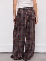 Pantalón de corte ancho y relajado, con estampa a cuadros en tonos marrones y azules. Cuenta con cintura elástica con cordón de ajuste y bolsillos laterales.