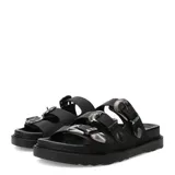 Sandalias de mujer Miss Carol Valencia, de color negro con tres tiras anchas en el empeine, cada una con hebillas metálicas plateadas de diseño occidental y punteras grabadas. Presentan suela plana con plataforma ligera y plantilla acolchada.