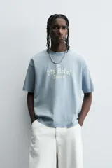 Camiseta de manga corta y cuello redondo, color celeste lavado, con estampado frontal en blanco que dice "The Mr. Rebel Dance".