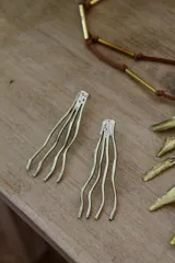 Par de caravanas colgantes doradas con forma de tentáculos.