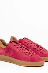 Zapatilla de cuero vacuno color rojo, con cordones al tono y suela de caucho color caramelo. Detalle de cuero vacuno color tostado en el talón.