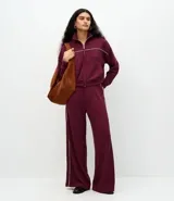 Pantalón wide leg color bordó con cintura estructurada y detalle de piping lateral en color blanco. Confeccionado en tejido de algodón, viscosa y poliéster.
