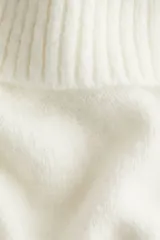 Buzo corto de punto suave color blanco, con escote off-the-shoulder con doblez ancho acanalado. Tiene remate acanalado en puños y bajo.