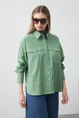 Camisa blanca de algodón con diseño utilitario y calce relajado. Presenta dos bolsillos frontales de estilo cargo con tapa y costuras a contratono.