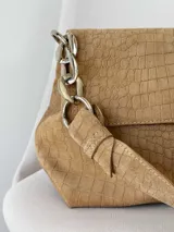 Cartera bandolera de cuero marrón con textura croco, solapa frontal, cierre metálico de giro plateado y correa de cadena con eslabones.