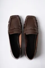 Mocasín de cuero marrón con textura arrugada, diseño de puntera cuadrada con detalle de costuras fruncidas en los laterales y banda frontal clásica.