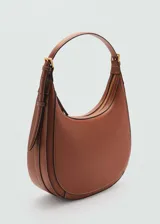 Bolso de hombro tipo hobo en color marrón, con diseño de media luna, costuras decorativas visibles y asa ajustable con hebillas laterales.