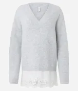 Suéter de punto color gris con escote en V y mangas largas. Presenta un diseño alargado con un detalle de encaje blanco en el ruedo inferior.