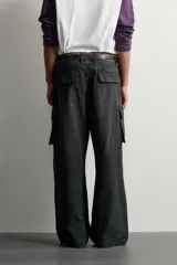 Pantalón cargo de corte relaxed fit, color negro con efecto lavado y estampado de salpicaduras blancas. Cuenta con bolsillos laterales con solapa en las perneras, pinzas en las rodillas y cierre frontal con botón y cremallera.