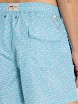 Short de baño celeste de RKF, confeccionado con poliéster reciclado. Presenta un estampado integral de pequeños pingüinos, cintura elástica con cordón ajustable blanco y gris, y bolsillos laterales.