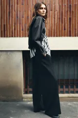 Pantalón de tiro alto color bordó, con pinzas delanteras, bolsillos frontales y falsos bolsillos con solapa en la espalda. Tiene pernera ancha y cierre frontal con cremallera, botón interior y gancho.