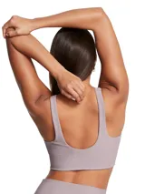 Top deportivo Under Armour Meridian Rib Bralette de color lila, confeccionado en tejido de punto acanalado elástico. Presenta un escote en V profundo, tirantes anchos y diseño alargado que favorece la figura, ideal para soporte ligero y entrenamiento.