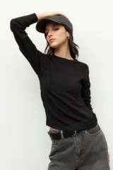 Remera negra de manga larga con cuello redondo y costuras a la vista.