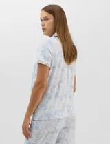 Conjunto de pijama de tres piezas en color celeste con estampado floral blanco y detalles de puntilla de encaje. Incluye una musculosa de breteles finos con escote en V, un capri con cintura elástica y cordón ajustable, y una camisa a juego.