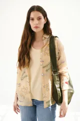 Camisa blanca de tela liviana y ligeramente arrugada, con bordados de motivos marinos en tonos azul, verde y ocre. Presenta cuello camisero, abotonadura frontal y mangas tres cuartos.