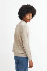 Sweater de punto color beige con cuello polo blanco y mangas largas.