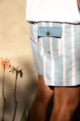 Short de baño celeste y blanco a rayas verticales, con cintura elástica y cordón ajustable.