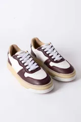 Championes urbanos de cuero con diseño de paneles en color blanco y bordó. Presentan cordones blancos, suela de plataforma en tono crema y detalles perforados en la puntera.