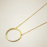 Collar de cadena fina con dije circular de diseño minimalista, elaborado en plata 925 con baño de oro y detalles de circonias engastadas en parte del contorno.