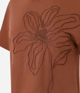 Remera de manga corta color marrón, con cuello redondo y corte recto. Presenta un bordado grande en relieve de una flor en el centro del pecho.