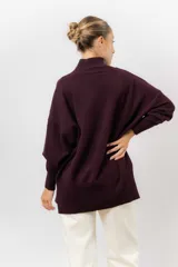 Sweater de tejido de punto color beige, con cuello alto, hombros caídos, mangas largas con puños acanalados y tajos laterales en el ruedo.