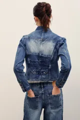 Saco de denim azul con efecto deslavado, corte entallado, cuello mao, mangas largas y cierre frontal con botones metálicos. Cuenta con bolsillos frontales appliquéd y un diseño de costuras estructuradas con dobladillo en punta.