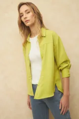 Camisa blanca de manga larga con textura arrugada, cuello camisero y botones frontales. Presenta un corte holgado y puños anchos con tres botones.