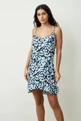 Vestido corto sin mangas con tirantes finos, escote redondo y diseño estampado en tonos azul, negro y blanco, con detalle de volados en el borde inferior.