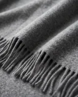 Poncho de abrigo color gris con flecos en el borde inferior y diseño envolvente.