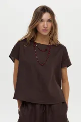 Blusa marrón de lino con cuello bote y mangas cortas suavemente caídas.