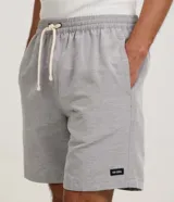 Bermuda de sarga color beige, de corte recto, con cintura elástica y cordón ajustable. Cuenta con bolsillos laterales y un discreto parche con logo aplicado en el dobladillo inferior.