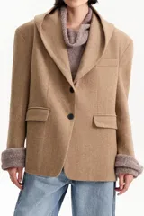 Tapado corto tipo blazer confeccionado en lana de color tostado. Presenta una capucha integrada, cierre frontal con dos botones negros y bolsillos laterales con solapa.