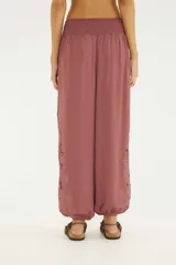 Pantalón aladín de silueta amplia y caída fluida, color rojo, con cintura elástica ancha con bordado y bajos de pierna fruncidos. Presenta detalles de bordado Richelieu en los laterales de las piernas.