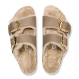 Sandalias Birkenstock modelo Arizona con forro de piel de oveja, correas de gamuza color tabaco y hebillas grandes doradas. Presenta la clásica plantilla de corcho y suela de goma negra.