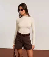 Short de sarga color blanco, corte mom, tiro alto, con trabillas en la cintura y bolsillos. Tiene cierre tradicional por botón y cremallera.