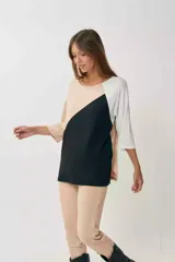 Remerón de manga tres cuartos con diseño tricolor en bloques diagonales: negro en el centro, beige claro en la parte superior izquierda y blanco en la manga derecha.