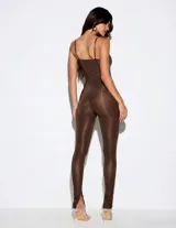 Mono largo de calce al cuerpo y acabado satinado, color marrón chocolate. Diseño con escote profundo tipo halter, tirantes finos y perneras ajustadas con aberturas en los tobillos.