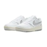 Championes Nike Gamma Force de diseño urbano, con base blanca y detalles en plateado metalizado en el logo lateral y el talón. Presenta una suela de plataforma en tono crema con acabado gris en la parte inferior.