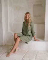 Vestido camisero de lino color marrón, de corte recto y largo midi, con mangas largas abotonadas, cuello camisero y cierre frontal con botones de nácar.