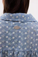 Camisa celeste a rayas verticales blancas, con cuello clásico, cierre frontal con botones y mangas largas abullonadas con puños elásticos.