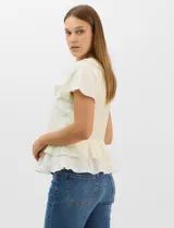 Blusa de satén color rosado con acabado texturizado, escote en V con volados, mangas cortas acampanadas y diseño péplum de doble nivel en la parte inferior.