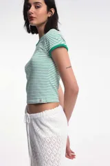 Remera baby blanca de algodón, de corte cropped al cuerpo y mangas cortas. Presenta ribetes negros en contraste en el cuello redondo y los puños, con un estampado localizado de un ají rojo con la inscripción 'Pimentón' en el centro del pecho.