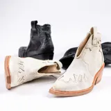 Botín de cuero vacuno color marrón oscuro, con taco de madera foliado en cuero de 5cm de altura, cierre lateral interno y horma de punta fina.