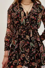 Vestido corto negro de manga larga con escote en V y frunces en la cintura. Presenta un estampado paisley multicolor vibrante.